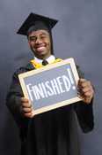 A boy in graduation regalia holds a sign that says 