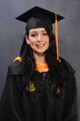 A girl in graduation regalia smiles for a photo