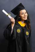 A girl in graduation regalia smiles while holding a diploma.