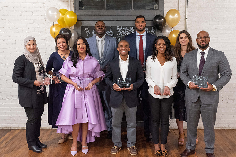 The winners of this year's 10 Under 10 awards pose for a photo. Behind them are black, yellow and white balloons.