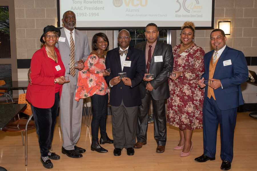 Men and women smile for a photo while holding awards.