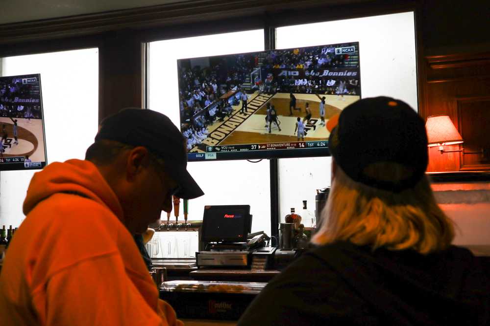A man and women watch a basketball game at a bar.