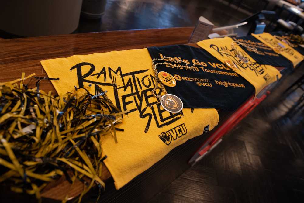 A t-shirt, pom-pom, button and other V-C-U alumni swag sit on a table.