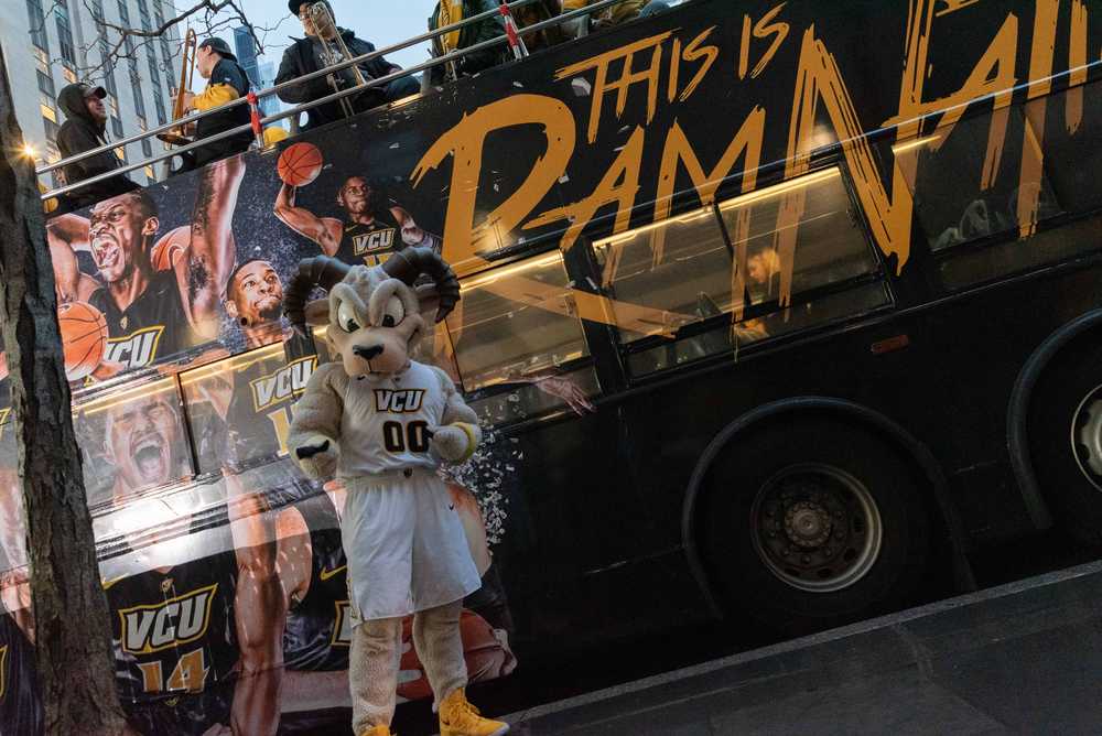 V-C-U mascot Rodney the Ram poses for a photo in front of a bus.