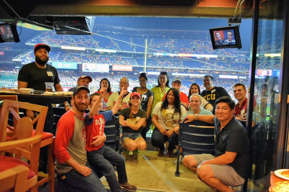 A group of V-C-U alumni pose for a photo at a baseball park.