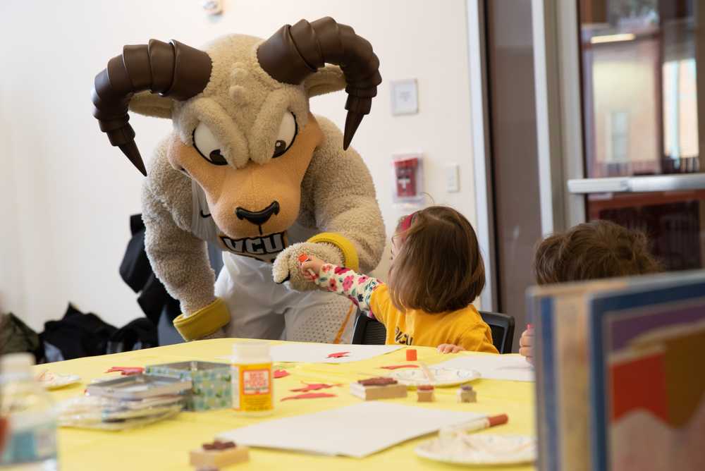 V-C-U mascot Rodney the Ram fist bumps a child during a reading event.