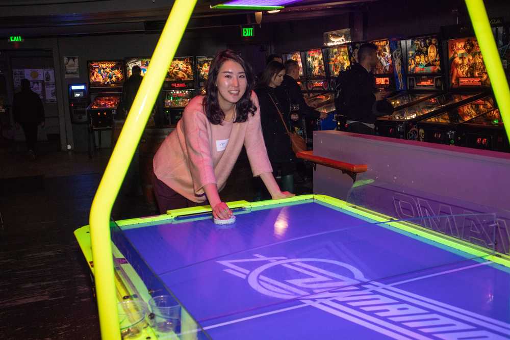 A woman plays air hockey at a barcade.