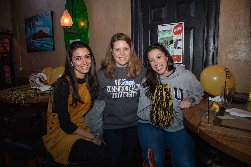 Three women smile for a photo taken at a basketball watch party.