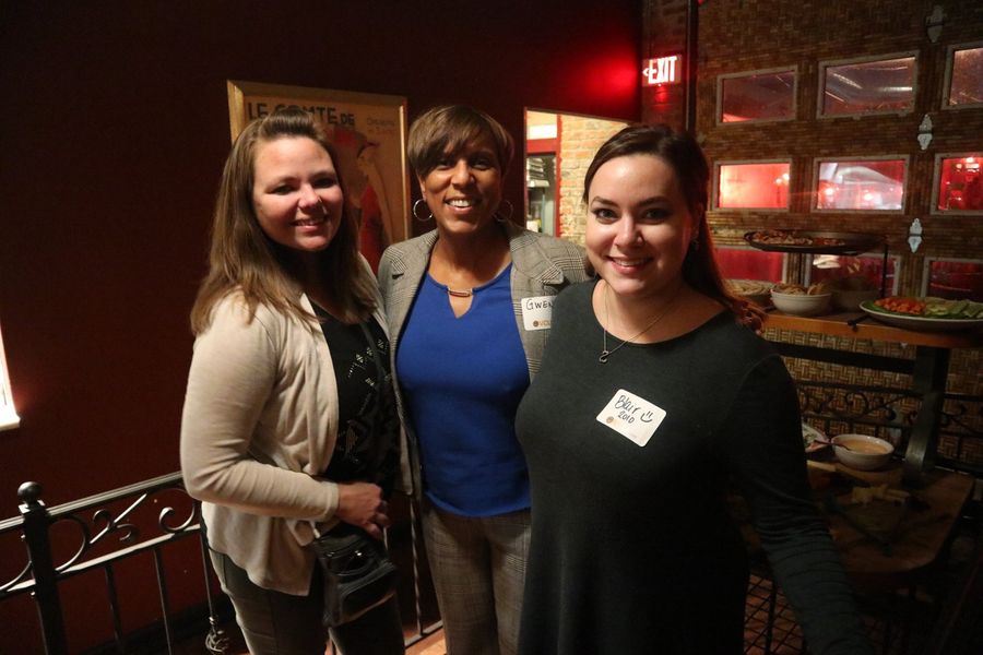 Three women pose for a picture at a bar.